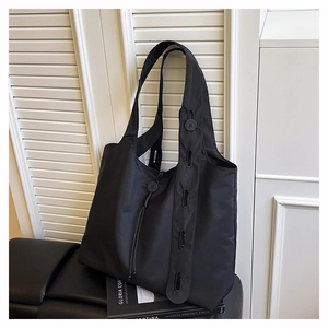 Detail of black nylon tote bag with unique button shoulder strap and drawstring closure