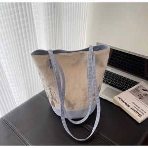 Detail of canvas tote bag with butterfly prints and metal rivets in a lifestyle office setting