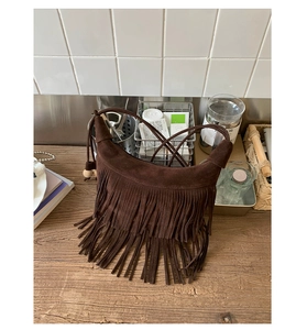 Dettaglio borsa a mezzaluna in pelle scamosciata marrone scuro con nappe bohémien