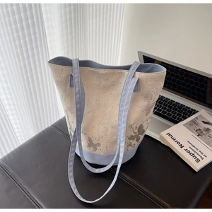 Detail of canvas bucket bag with butterfly print and blue trim in a modern lifestyle setting