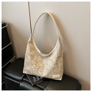 Close-up of floral canvas hobo tote bag with fashion logo on a leather bench