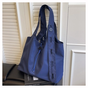 Detail of navy nylon tote bag with adjustable button strap and drawstring closure
