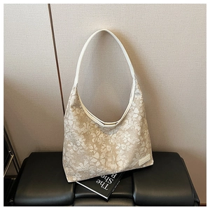 Detail of floral beige hobo bag with white strap and vintage pattern texture