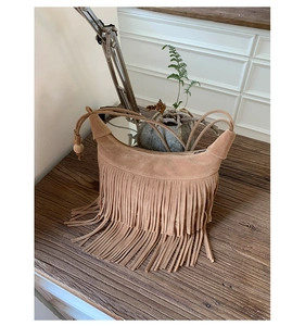 Dettaglio borsa hobo scamosciata boho con lunghe frange e decorazioni in perline di legno
