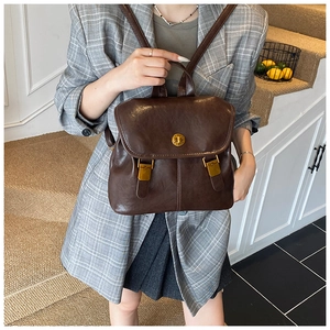 Detail view of vintage dark brown leather backpack with gold clasp and buckle straps