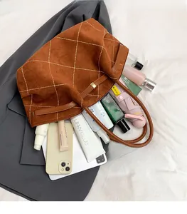 Detail view of large brown suede tote bag featuring white diamond stitching and ample space