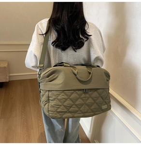 Detailed macro view of olive green quilted stitching and nylon texture on travel tote