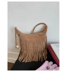 Dettaglio borsa a tracolla boho in camoscio marrone con frange e perline di legno