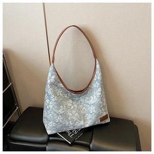 Detail of floral jacquard fabric and brown leather strap on a large shoulder tote bag