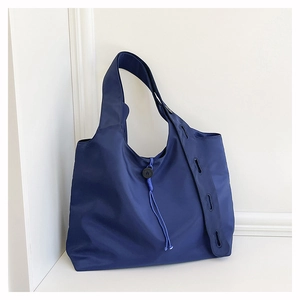 Close-up of dark blue nylon tote bag featuring drawstring detail and grommeted straps
