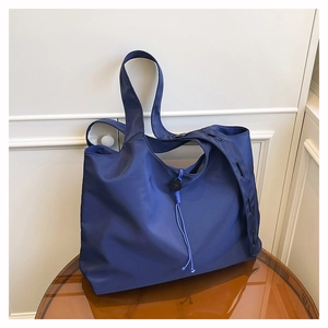 Detail view of foldable nylon tote bag in deep blue with drawstrings and round clasp