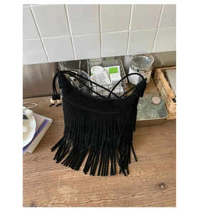Dettaglio ravvicinato della borsa a tracolla boho in camoscio nero con lunghe frange