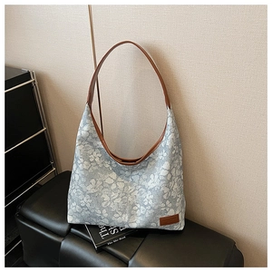 Detailed macro view of retro floral tote bag with brown leather handles and branding