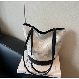 Detail of canvas tote bag featuring butterfly print and rhinestone accents on white fabric