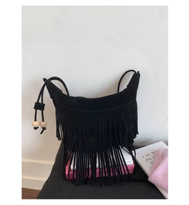 Dettaglio della borsa boho in camoscio nero con lunghe frange e cinturino in legno