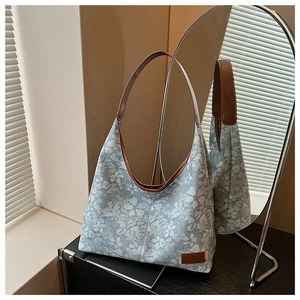 Detailed close-up of blue floral hobo bag with brown leather strap and brand patch