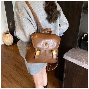 Detail view of retro brown leather backpack with gold metal hardware on model