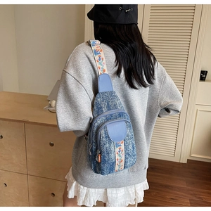 Detailed view of blue denim crossbody bag featuring colorful floral embroidered strap