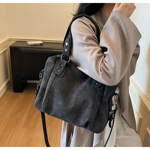 Detailed view of grey frosted leather tote bag with silver rivets and adjustable strap