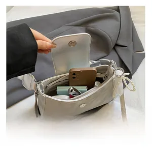 Internal view of silver shoulder bag showing storage for phone, lipstick, and makeup