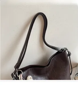Detail view of dark brown tote bag with leather grain texture and plush bear pendant