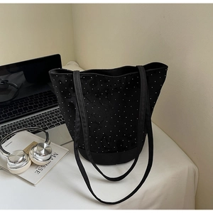 Detail of black canvas tote bag with white polka dot rivets on office desk setup