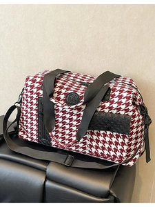 Large red and white houndstooth travel bag with black straps and adjustable shoulder strap