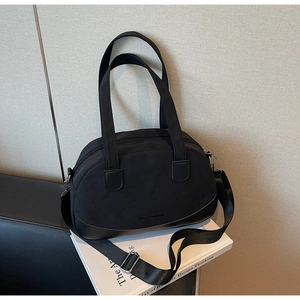 Detail of a black mini shell bag featuring high-density nylon and a leather-stitched base
