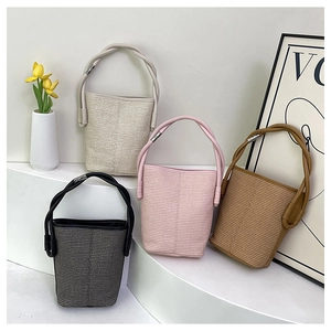 Detailed view of woven bucket bags in cream, pink, black and brown on tiered display