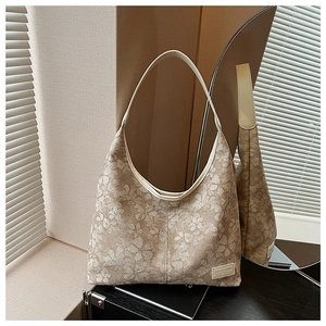 Close-up of beige jacquard tote bag with white clover patterns and leather shoulder strap