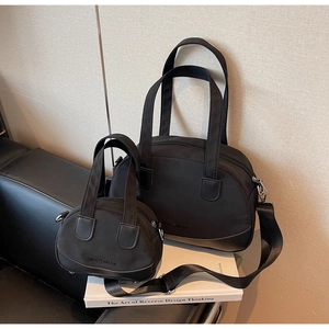 Detail view of two-piece black nylon and leather mini shell bags on white books