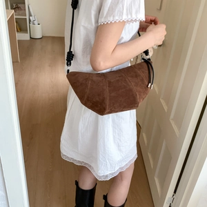 Détail du sac croissant en daim marron montrant la texture et la bandoulière nouée