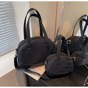 Detail of minimalist black nylon tote and mini shell bag with sleek branding logo