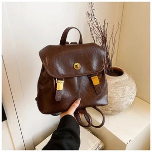 Detail of vintage dark brown leather backpack featuring a golden twist lock closure