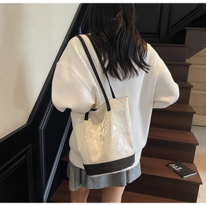 Side view of a canvas bucket bag with butterfly prints and black rivet details worn by a model
