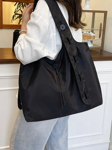 Large capacity black nylon tote bag with adjustable straps shown in a lifestyle cafe setting