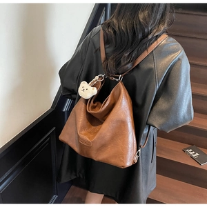 Macro detail of vintage brown leather backpack with adjustable straps and bear charm