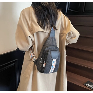 Grey canvas crossbody bag with floral strap shown on model in a stylish indoor setting