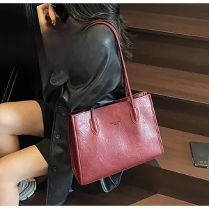 Detail of burgundy leather tote bag showing textured finish and sleek shoulder strap