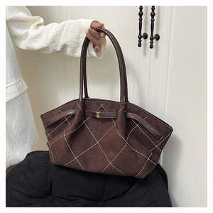 Detail of brown suede tote bag featuring white quilted stitching and metal buckle closure