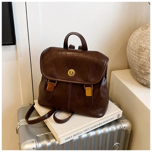 Close-up of a vintage brown leather backpack with gold metal buckle and smooth texture