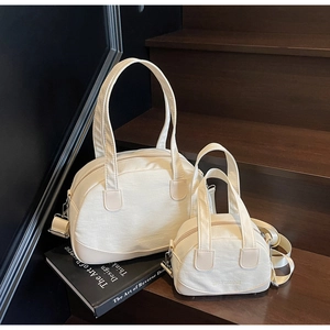 Detailed view of cream canvas tote set in two sizes with faux leather trim and strap