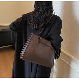 Detail of large dark brown tote bag with fashion trend engraving on vintage wax leather