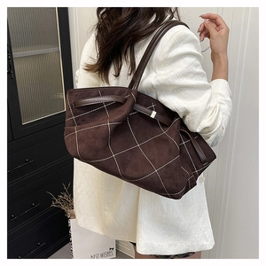 Detail of dark brown suede tote bag featuring white diamond stitching and long straps