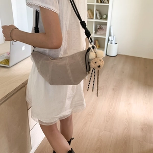 Détail du sac croissant en daim kaki avec matelassage vertical et breloque ours mignon