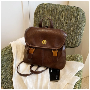 Detail of vintage dark brown faux leather backpack featuring golden buckles and metal logo