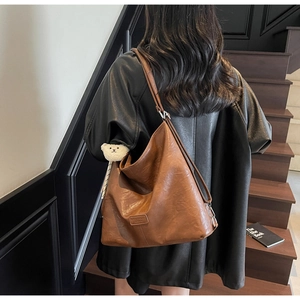 Detail of vintage brown leather hobo bag with teddy charm and adjustable shoulder strap