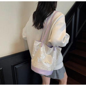 Dettaglio della borsa tote in jacquard bianco con motivi a farfalla e bordi viola