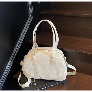 Detailed close-up of cream canvas shell bag on wooden stairs with branded logo text