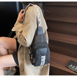 Detail of dark gray canvas chest bag featuring colorful ethnic embroidered shoulder strap